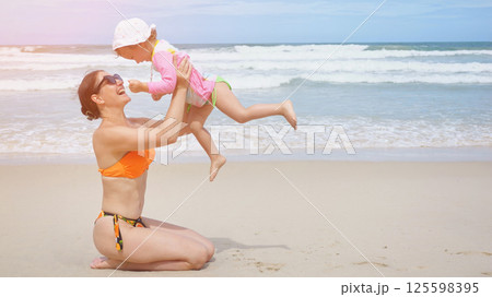 Mother and daughter playing on the beach 125598395