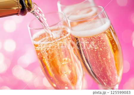 Close-up of pink champagne being poured into a flute glass with bubbles sparkling against a soft pink bokeh background. Perfect for holidays, romantic moments, weddings and special occasions. Banner 125599083