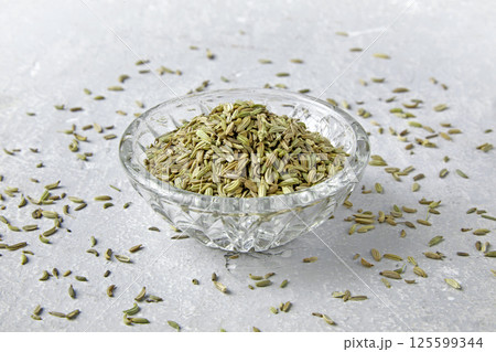 fennel seeds in a crystal bowl scattered on a gray stone table fennel seeds in a crystal bowl scattered on a gray stone table 125599344