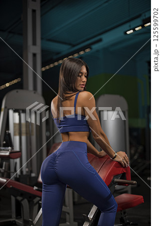 woman demonstrates her strength and fitness approach in well equipped gym. She confidently poses near workout equipment highlighting her dedication wellness and health. woman demonstrates her strength and fitness approach in well equipped gym. She confidently poses near workout equipment highlighting her dedication wellness and health. 125599702