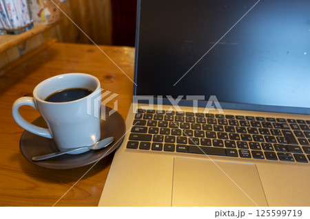 テーブルに置かれたノートパソコンとコーヒー 125599719