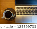 机の上に置かれたノートパソコンとコーヒー 125599733