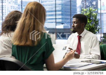 Team of headhunters tasked with hiring best talent to fill open company position, interviewing person. HR coworkers hired to assess skills and qualifications of candidate, doing meeting in office 125599784
