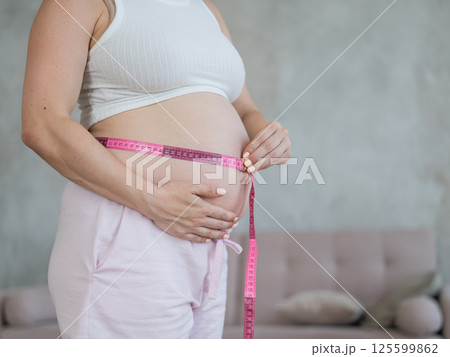 Pregnant woman measuring her belly.  125599862