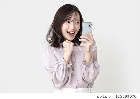 スマホの画面を見て嬉しそうに笑顔で喜ぶ若い女性 スマホの画面を見て嬉しそうに笑顔で喜ぶ若い女性 125599970