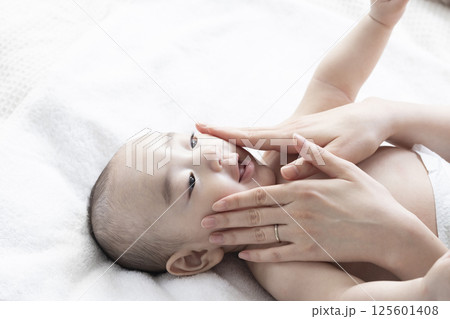 赤ちゃんにベビーマッサージをするママ 125601408