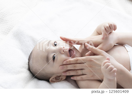 赤ちゃんにベビーマッサージをするママ 125601409
