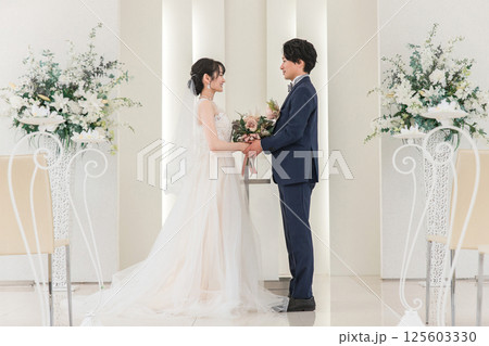 結婚式場でブーケを持って見つめ合う新郎新婦(ウェディング・ブライダル・夫婦) 125603330
