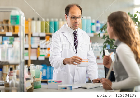 Pharmacist offering pills to woman buyer Pharmacist offering pills to woman buyer 125604138
