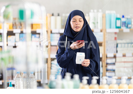 Young Muslim woman customer scanning QR-code on pills box Young Muslim woman customer scanning QR-code on pills box 125604167