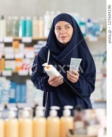 Young woman in hijab chooses cream at pharmacy 125604196