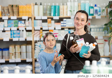woman keeps various goods, vitamins in a pharmacy with her daughter woman keeps various goods, vitamins in a pharmacy with her daughter 125604424