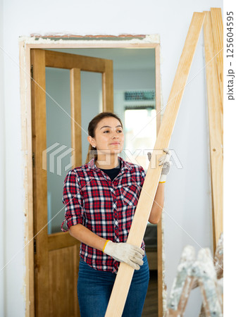 Woman carrying wooden planks during renovation works Woman carrying wooden planks during renovation works 125604595