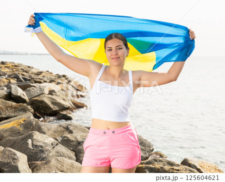 Young woman on coast posing with flag of Ukraine 125604621