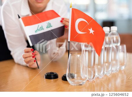 Little flag of Turkey on table and flag of Iraq put next to it by young woman 125604652