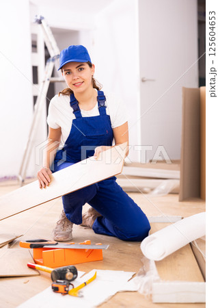 Female carpenter taking out laminate planks from package 125604653