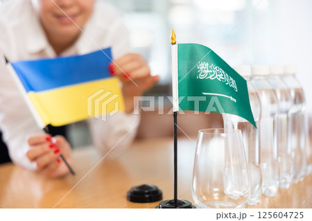 Flags of Ukraine and Saudi Arabia stand on negotiating table in office Flags of Ukraine and Saudi Arabia stand on negotiating table in office 125604725