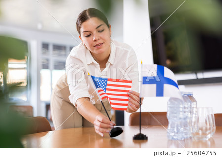 female assistant prepares conference room for diplomats of Finland and USA 125604755