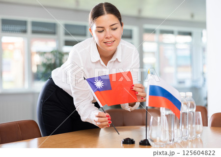 Young lady sets miniatures flags of Russia and Taiwan before international negotiations Young lady sets miniatures flags of Russia and Taiwan before international negotiations 125604822