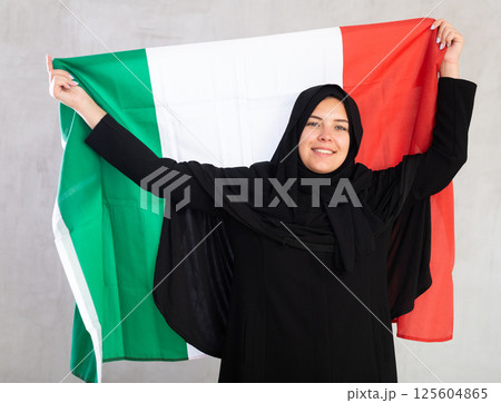 Happy young woman dressed in traditional islamic clothes with italian flag 125604865