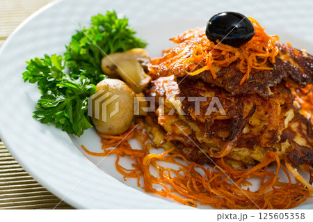 Vegetarian dish, carrots pancakes with mushrooms served at black plate Vegetarian dish, carrots pancakes with mushrooms served at black plate 125605358