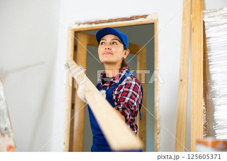 Female worker installing door jambs in room being renovated Female worker installing door jambs in room being renovated 125605371