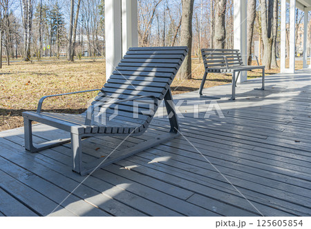 Empty grey wooden deck chairs or sun beds in city park. Concept of recreation, tanning Empty grey wooden deck chairs or sun beds in city park. Concept of recreation, tanning 125605854