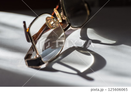 Eyeglasses on white table with shadow and sunlight in morning light Eyeglasses on white table with shadow and sunlight in morning light 125606065