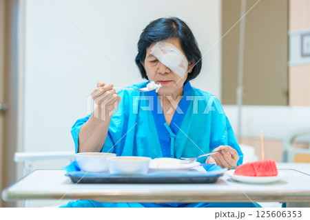 Senior Woman eating food after eye surgery in hospital . Eye disease, Cataract,  Glaucoma, Age Related Macular Degeneration, Diabetic Retinopathy, Lasik, World Glaucoma day and health treatment 125606353