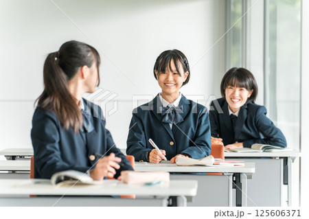 学校で授業中に後ろの席の生徒と話す小学生・中学生・高校生・女子高生（友達） 125606371
