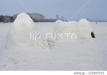 Igloo, national shelter from the cold of northern peoples, made of snow bricks, and city in distance 125607331