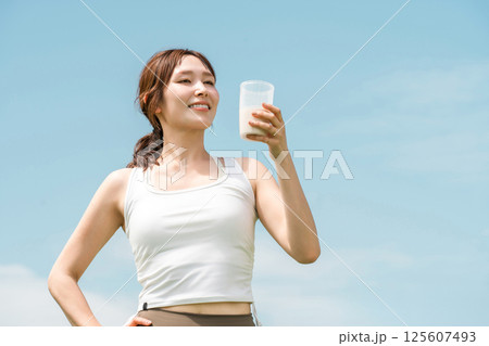 運動時にプロテイン・EAA・ドリンクを飲む女性(青空) 125607493