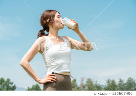 運動時にプロテイン・EAA・ドリンクを飲む女性(青空) 125607496