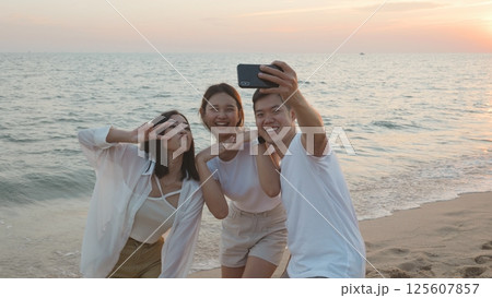 Happy friends smiling and posing taking selfie from smartphone and having fun together on beach in holiday vacation time at sunset, Young Asian group woman and man in summer travel outdoor 125607857