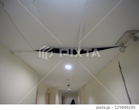 A ceiling with visible crack and recessed light fixture, indicating potential structural issues. scene conveys sense of neglect and requires 125608285