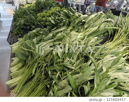 A fresh green vegetables, including leafy greens and herbs, are displayed in market setting, showcasing vibrant colors and textures A fresh green vegetables, including leafy greens and herbs, are displayed in market setting, showcasing vibrant colors and textures 125608457