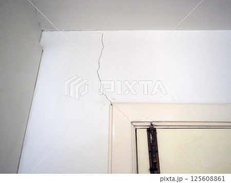 A cracked wall in room showing signs of damage and wear, highlighting structural issues and need for repair A cracked wall in room showing signs of damage and wear, highlighting structural issues and need for repair 125608861