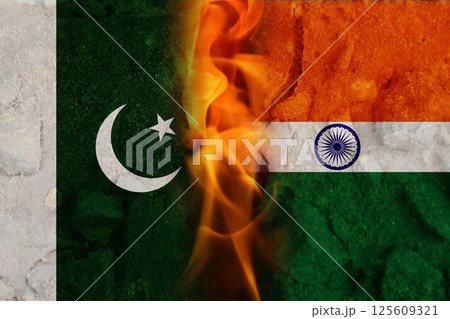 Abstract representation of India and Pakistan flags with flames and fire symbolizing conflict and tension along the border, with a military backdrop evoking a sense of war and unrest 125609321