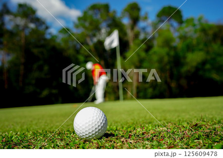 Golf ball on green grass in the evening golf course with sunshine background. Golf ball on green grass in the evening golf course with sunshine background. 125609478