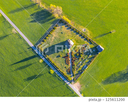 Aerial view of Tesarov Chapel nestled in the Jizera Mountains, showcasing a small graveyard and lush green landscapes of Korenov, revealing serene rural charm and historical significance. Aerial view of Tesarov Chapel nestled in the Jizera Mountains, showcasing a small graveyard and lush green landscapes of Korenov, revealing serene rural charm and historical significance. 125611200