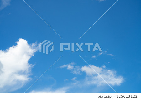 Blue sky with fluffy white cumulus clouds on bright sunny day, natural cloudscape background for environment and weather concepts. Summer day. Ozone awareness, clean air, environmental protection. 125613122