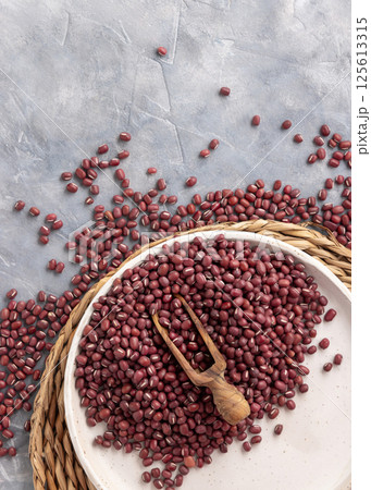 Plate full of dried red azuki beans with a wooden scoop top view. East Asian legumes, vegetarian food 125613315