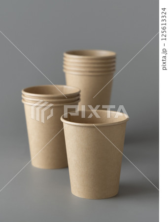 Disposable beige kraft paper cups on a gray closeup, mockup. No plastic and sustainable lifestyle 125613324