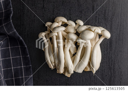 Raw white shimeji mushrooms on black table. Top view. 125613505