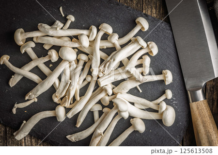 Raw white shimeji mushrooms on cutting board. Top view. Raw white shimeji mushrooms on cutting board. Top view. 125613508