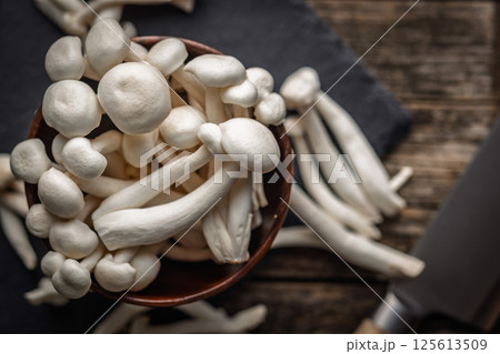 Raw white shimeji mushrooms on cutting board. Top view. Raw white shimeji mushrooms on cutting board. Top view. 125613509