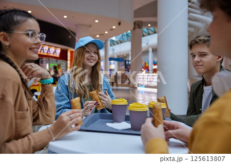 Teenage friends resting having refreshments at cafeteria in shopping mall 125613807