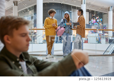 Teenage friends talking together ignoring boy while meeting in shopping mall 125613919