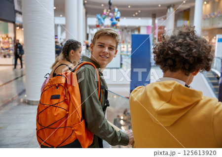 Excited teenage boy looking at camera while entertaining at shopping center 125613920