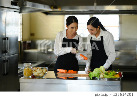 Female culinary student preparing fresh vegetables during a cooking class 125614201